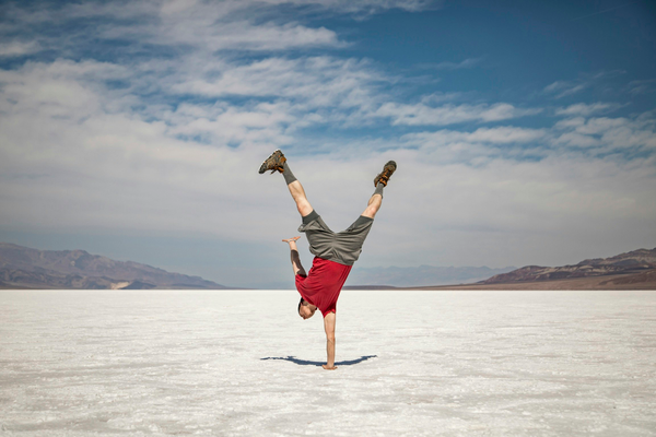 Person balancing on one hand in a salt flat