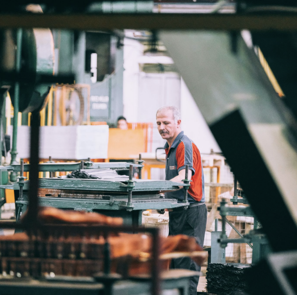 Image of a factory worker turning raw materials into finished goods in a real factory